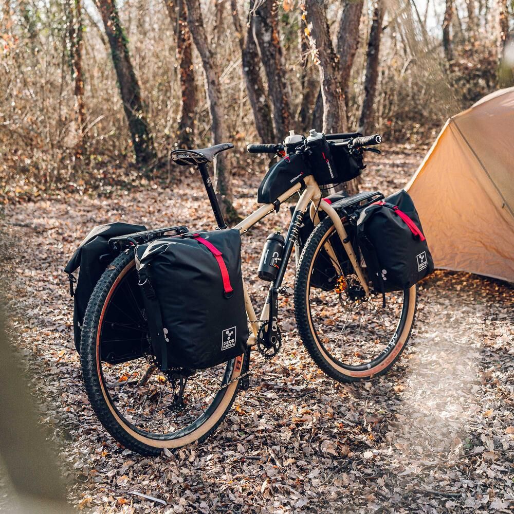Bicycle with pannier packs in a forest setting near a tent