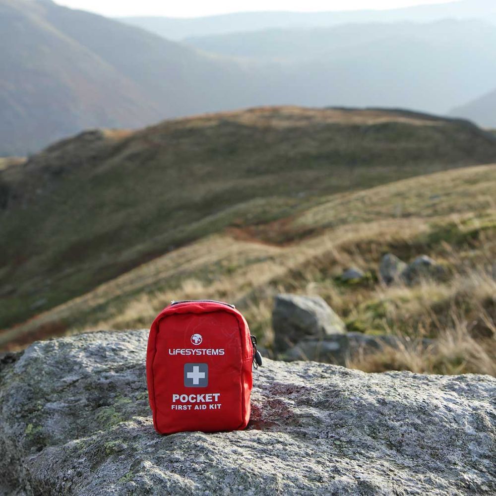 Red first aid kit on a rock with a mountainous background