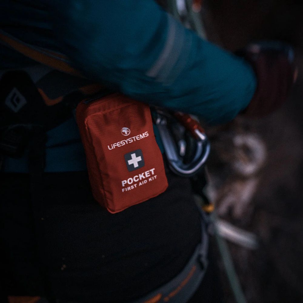 Red first aid kit labeled 'Lifesystems Pocket First Aid Kit' attached to a climbing harness.