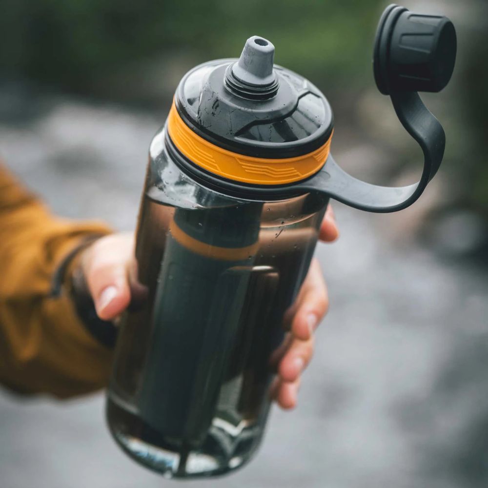 Person holding a black and orange water bottle with a blurred background