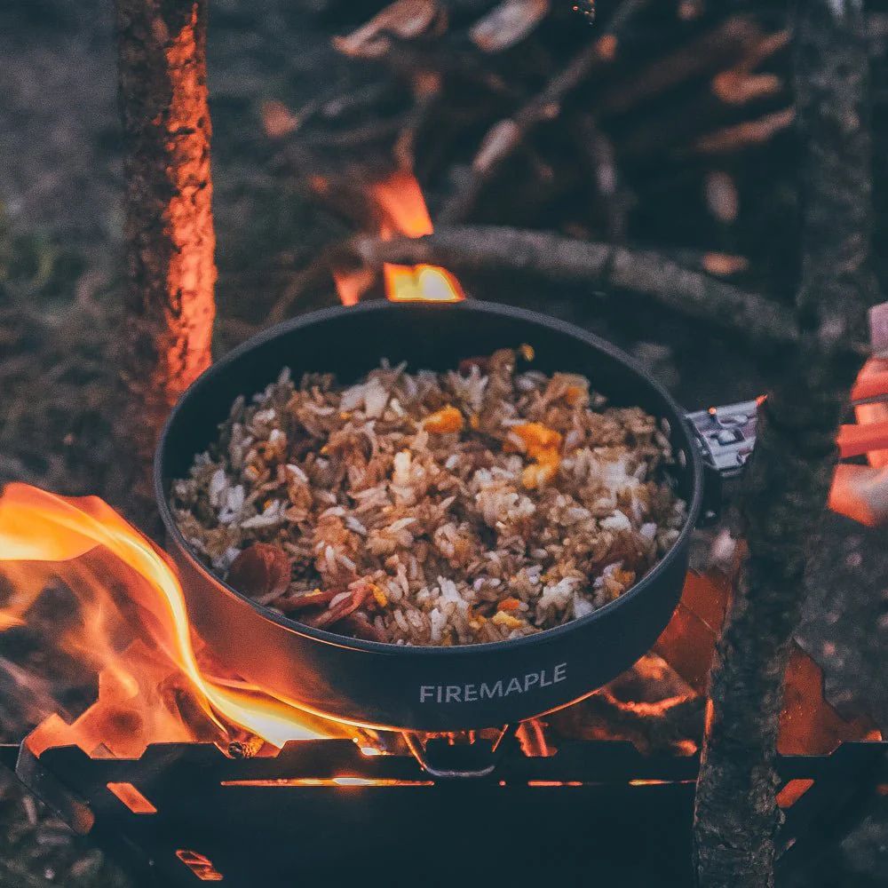 Cooking food in a pot over a campfire with 'Firemaple' branding.