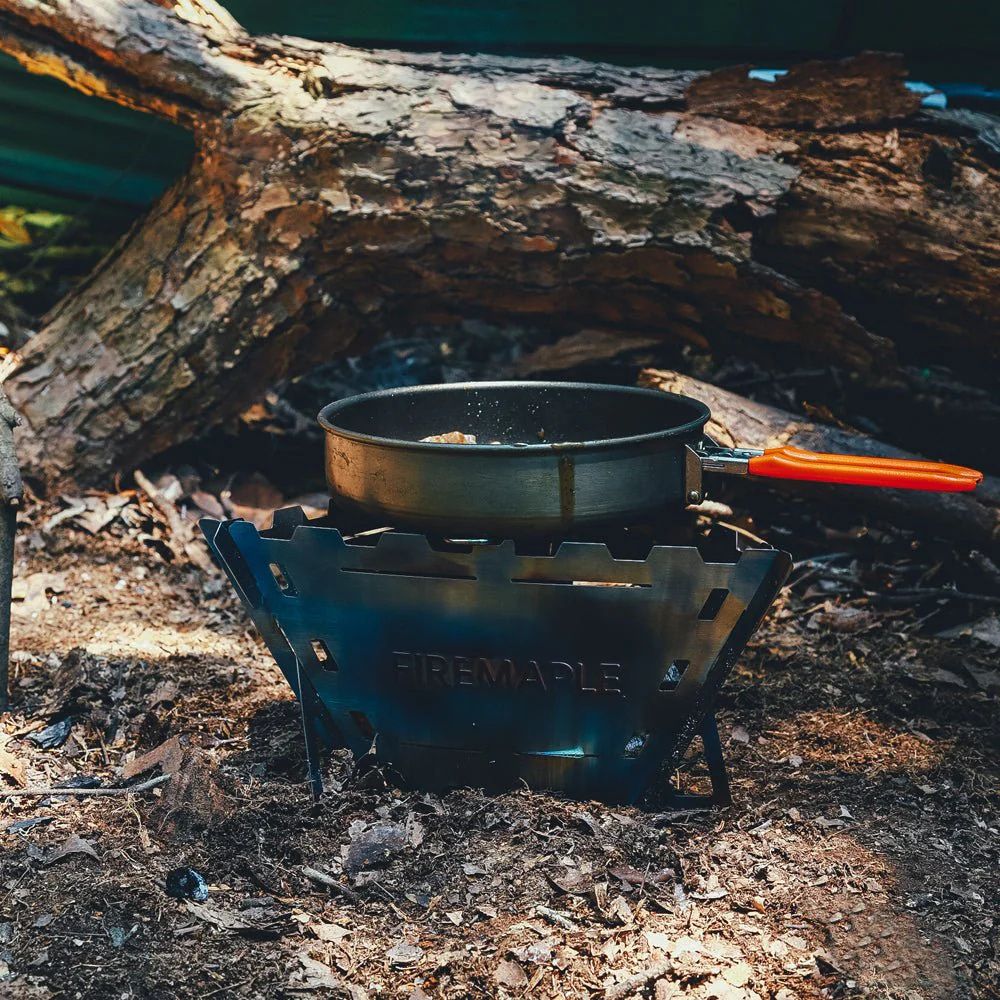 Camping stove with pot over a campfire in the woods