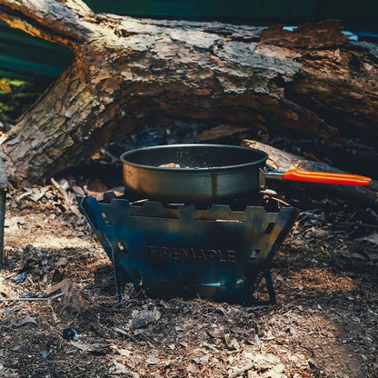 Camping stove with pot over a campfire in the woods