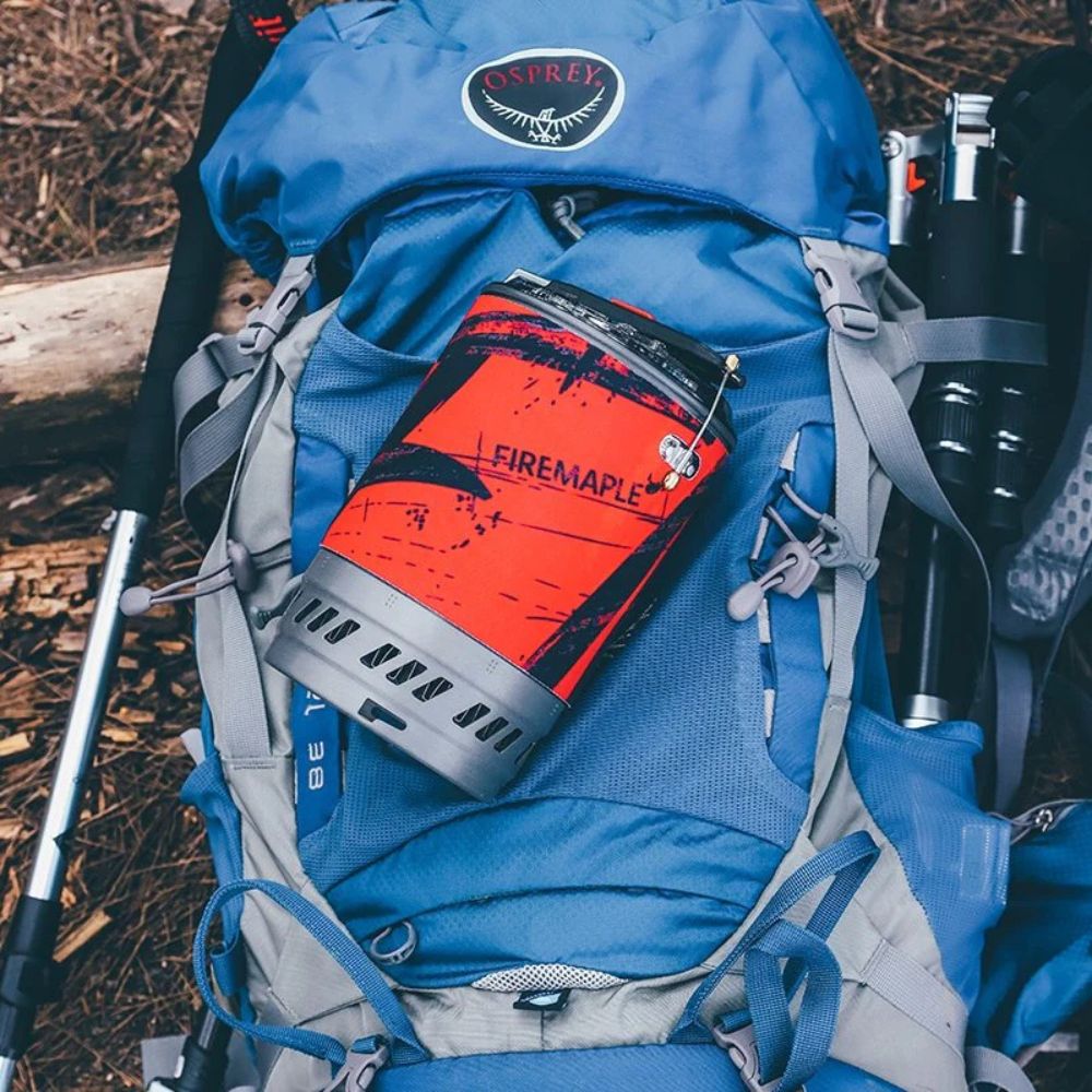 Blue Osprey backpack with a red Firemaple product attached, outdoors.