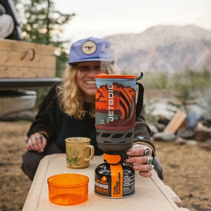 Person holding a Jetboil stove outdoors with mountains in the background