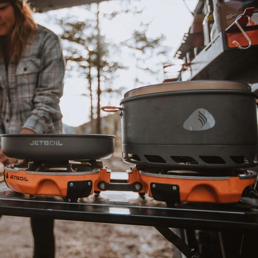 Jetboil camping stove and cookware on a table with a person in the background.