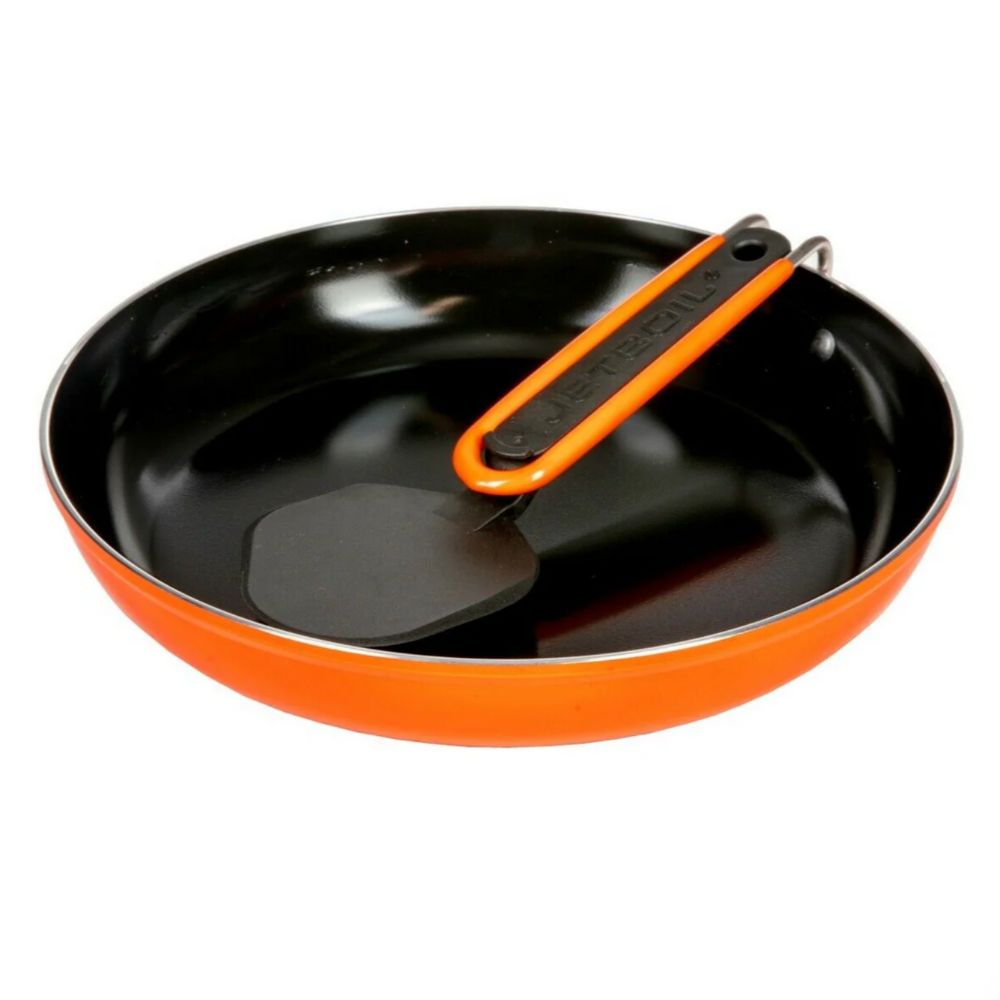 Black frying pan with orange handle and spatula on a white background