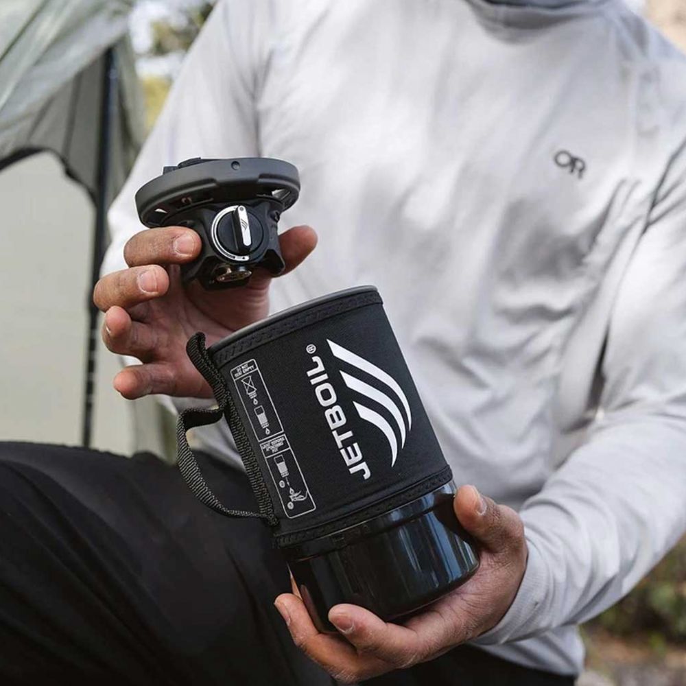 Person holding a Jetboil cooking system outdoors