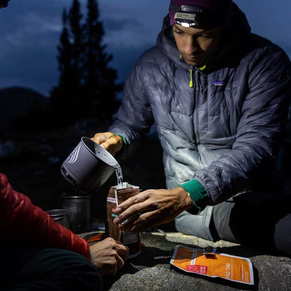 Person in outdoor setting pouring from a container into a mug