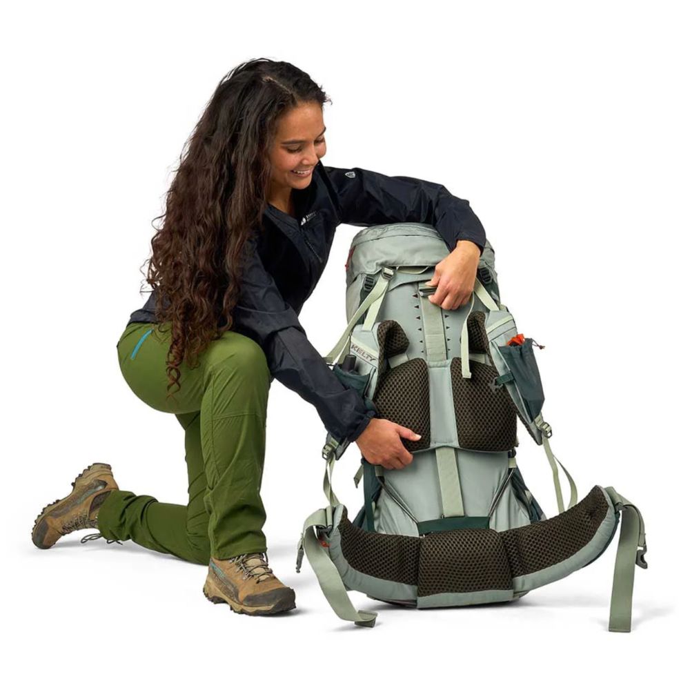 Person adjusting a large hiking backpack on a white background