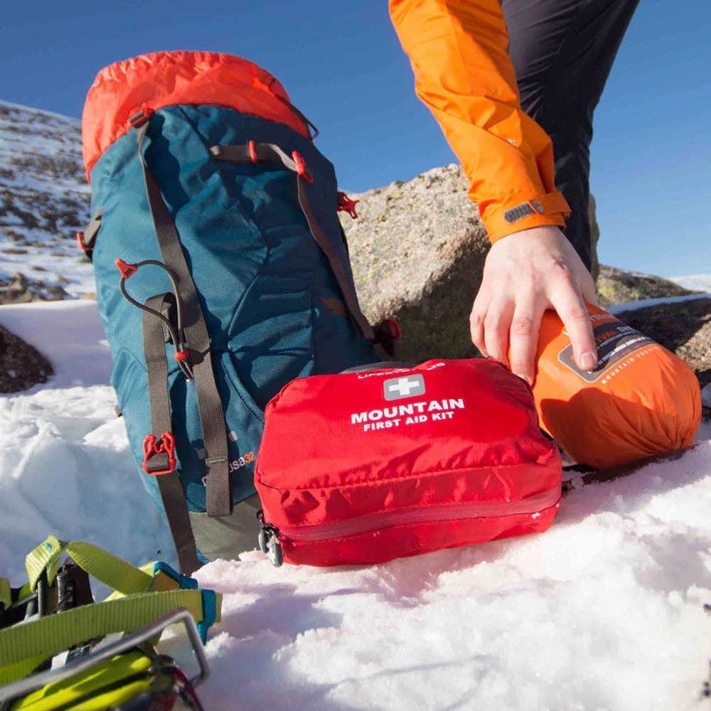 Person in orange jacket with a red mountain first aid kit on snow