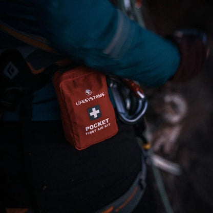 Red first aid kit labeled 'Lifesystems Pocket First Aid Kit' attached to a climbing harness.