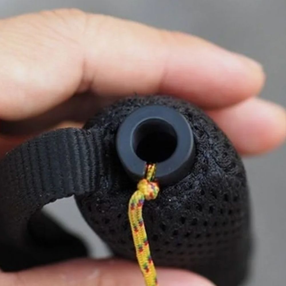 Black textured object with a colorful string held by a hand against a gray background