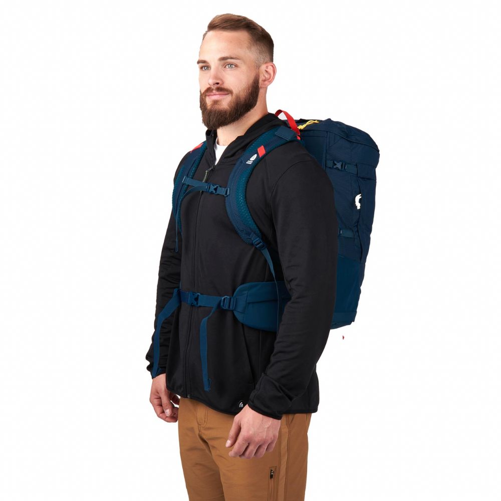 Man wearing a black jacket with a blue backpack on a white background