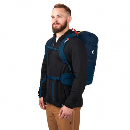 Man wearing a black jacket with a blue backpack on a white background